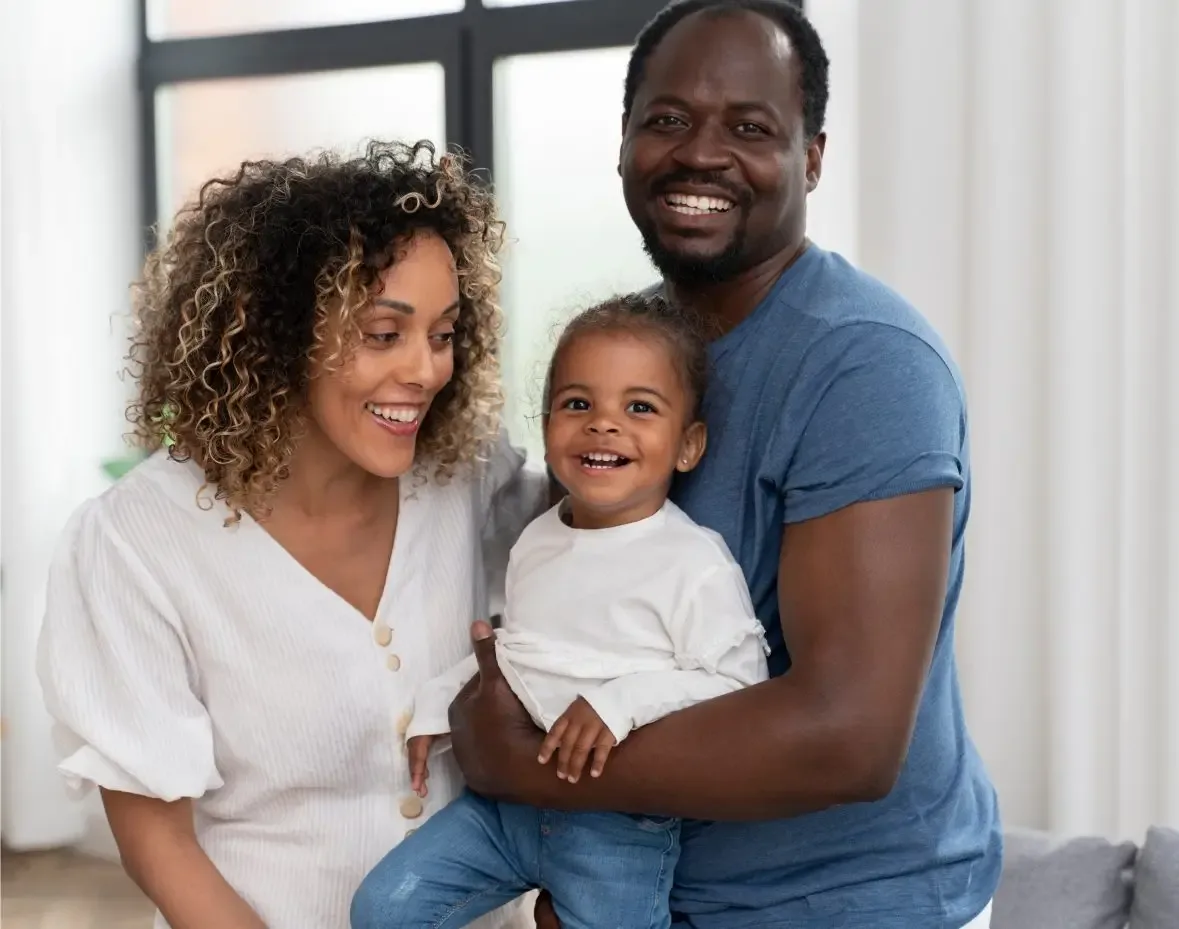 A smiling family: a mother, a father and their young child.