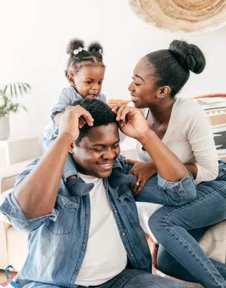 A father and daughter playing with their mother.