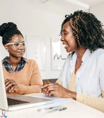 A specialist talking with a woman at a laptop.